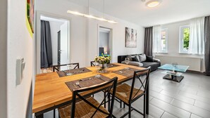 A modern dining area with a wooden table, black chairs, and a glass coffee table. - Ideal for Contractors: 2 Bedrooms for 4 Guests (65 m²) in Saarbrücken, Free Parking (Saarbrücken)