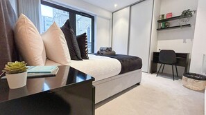Een moderne slaapkamer met een bed, nachtkastje en een bureau.