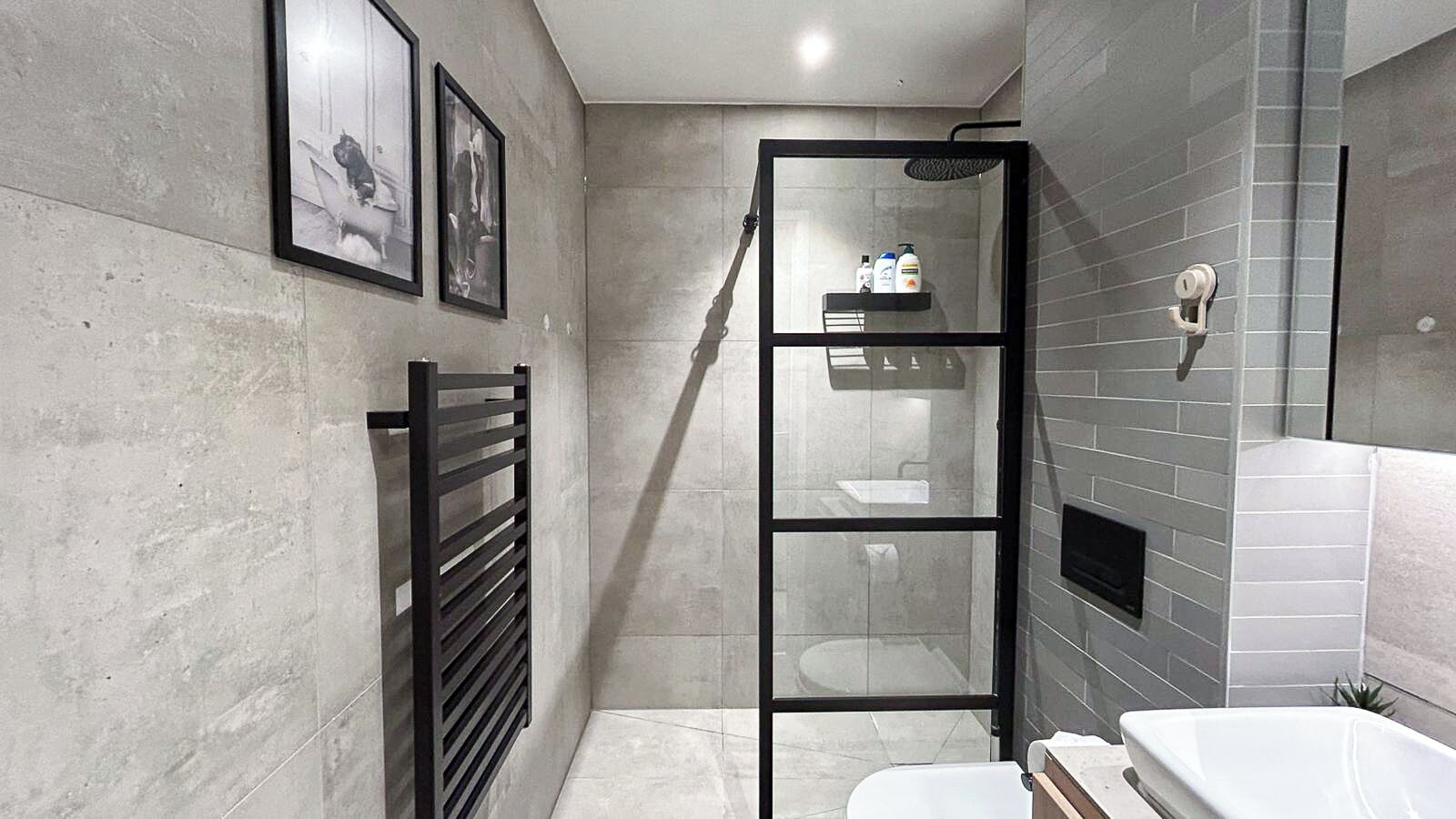 A modern bathroom with a glass-enclosed shower, a white sink, and a toilet.