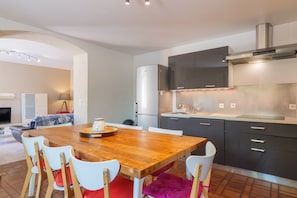 Une cuisine moderne avec une table en bois, des chaises blanches et des meubles de rangement sombres.