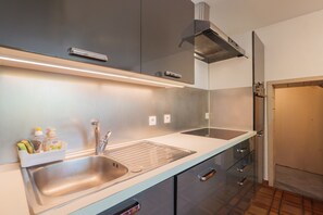 Une cuisine moderne Ă©quipĂ©e dâappareils Ă©lectromĂ©nagers en acier inoxydable, dâun Ă©vier Ă deux bacs et dâun four encastrĂ©.