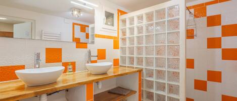 Baño con dos lavamanos, un espejo y zona de ducha.