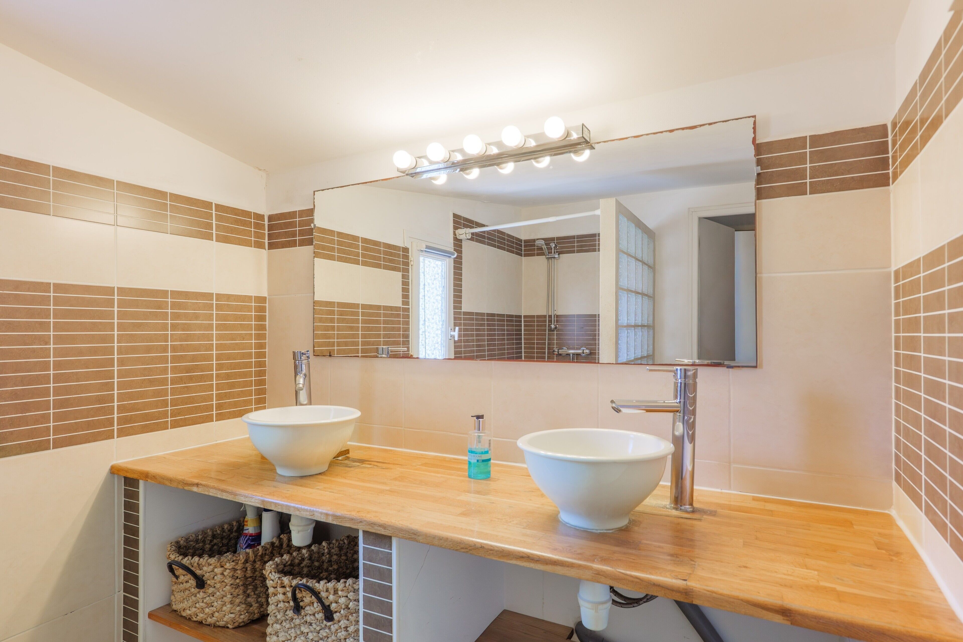 Een badkamer met twee wasbakken, een spiegel en een lamp erboven.
