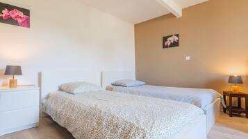 A bedroom with two beds, a nightstand with a lamp, and a wall-mounted picture.