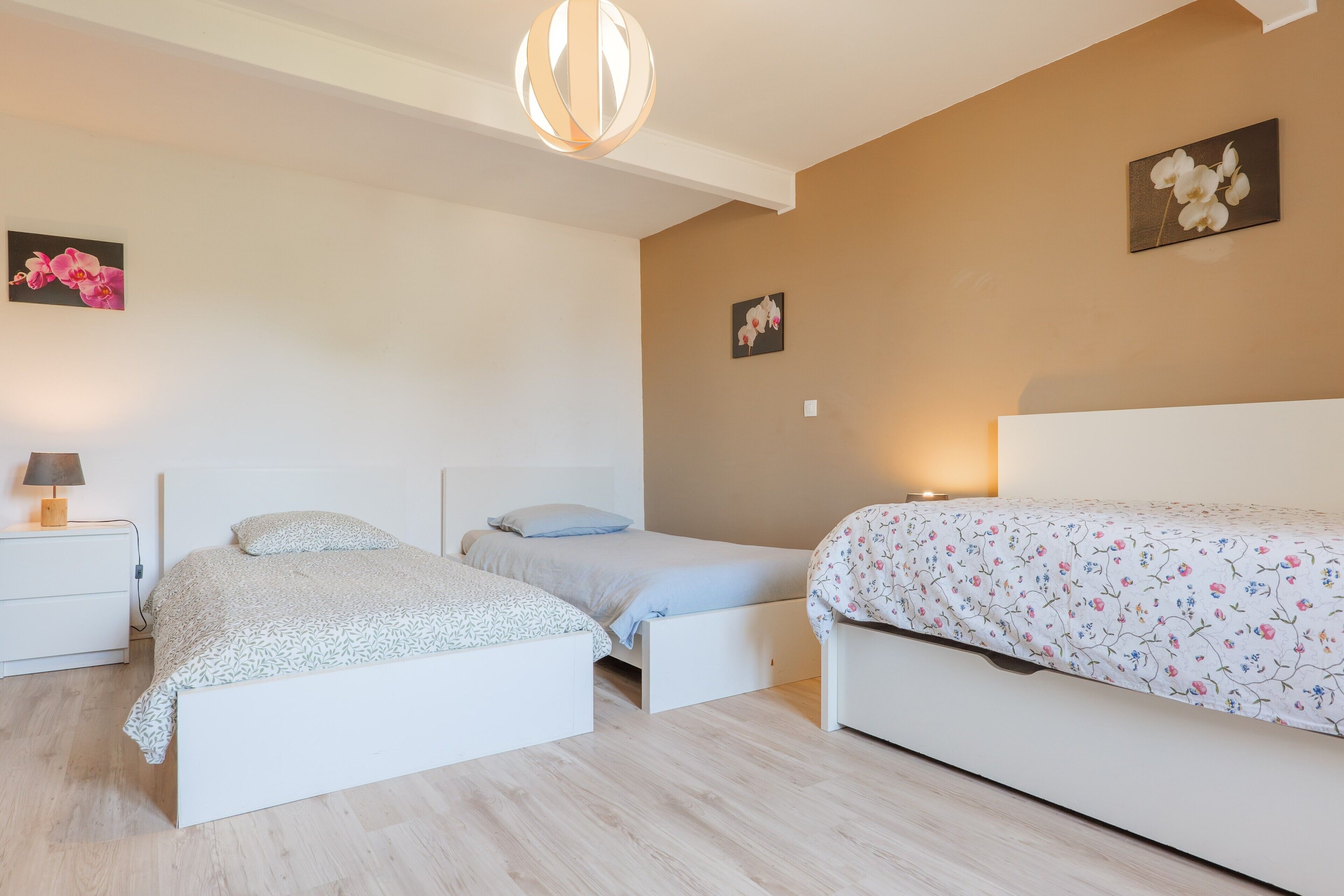 A bedroom with two beds, a bedside table, a lamp, and wall art.