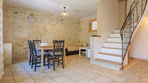 A dining area with a table and chairs, a sofa, a staircase, and a wall clock.