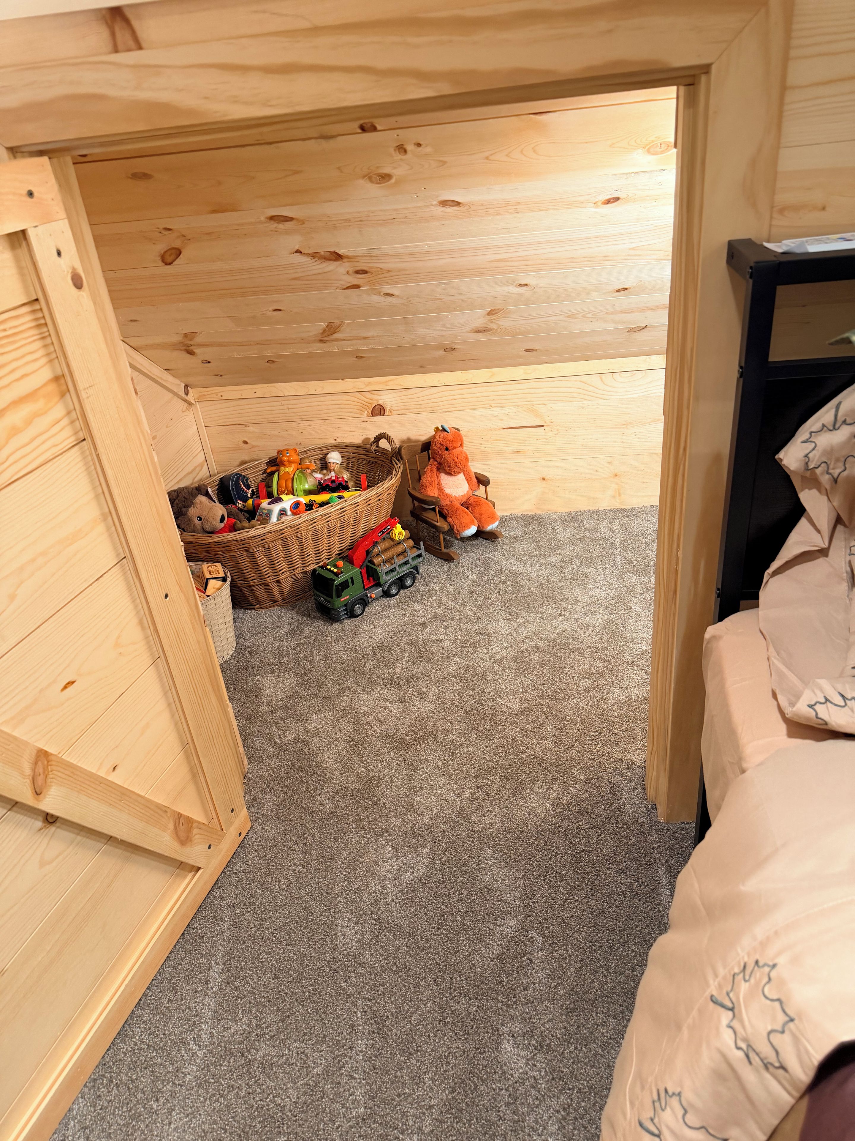 A child's playroom with a wooden bunk bed, a toy truck, and a stuffed animal.