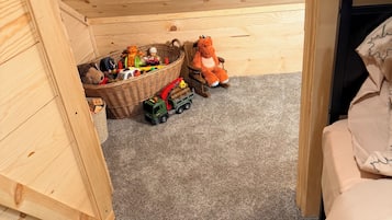 A child's playroom with a wooden bunk bed, a toy truck, and a stuffed animal.
