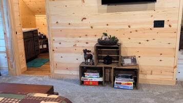 A room with two beds, a television mounted on the wall, and a small wooden shelf with items.