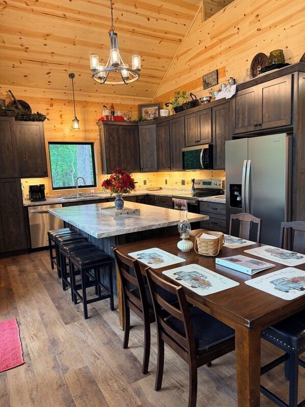 A modern kitchen with wooden cabinets, a stainless steel refrigerator, and a large window.