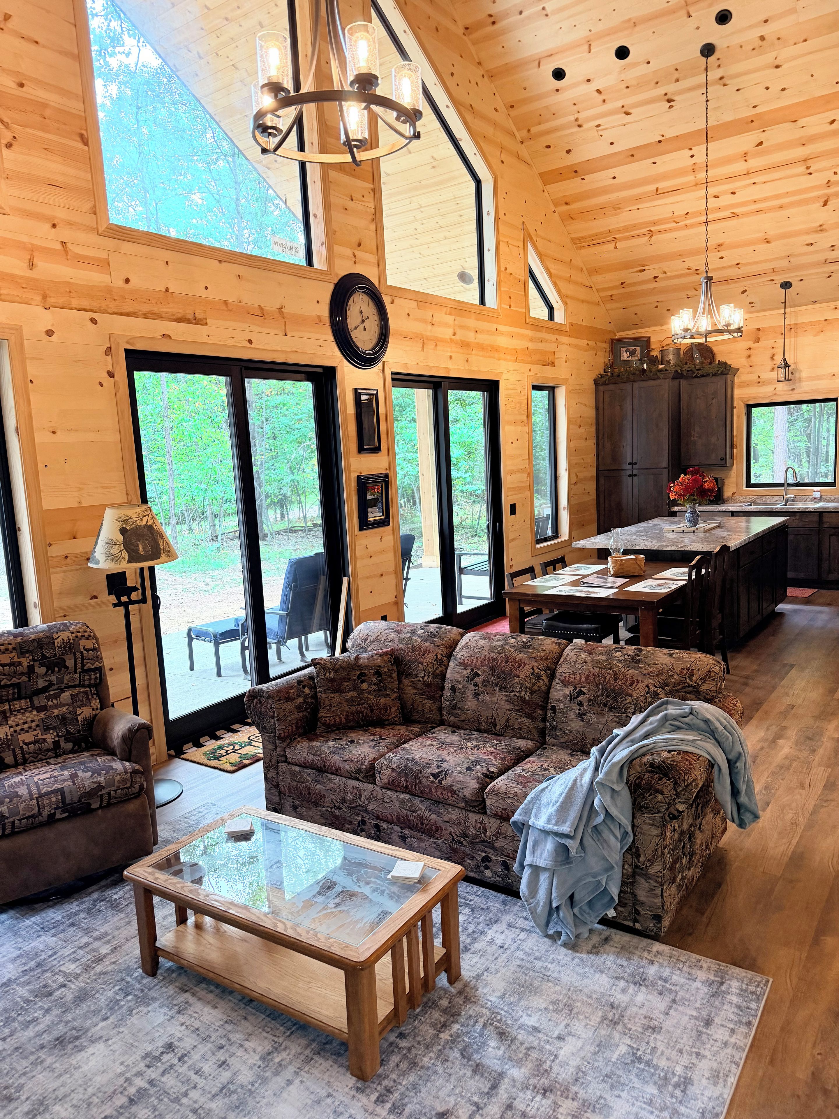 A spacious living room with a large sofa, a coffee table, and a dining area with a kitchen in the background.
