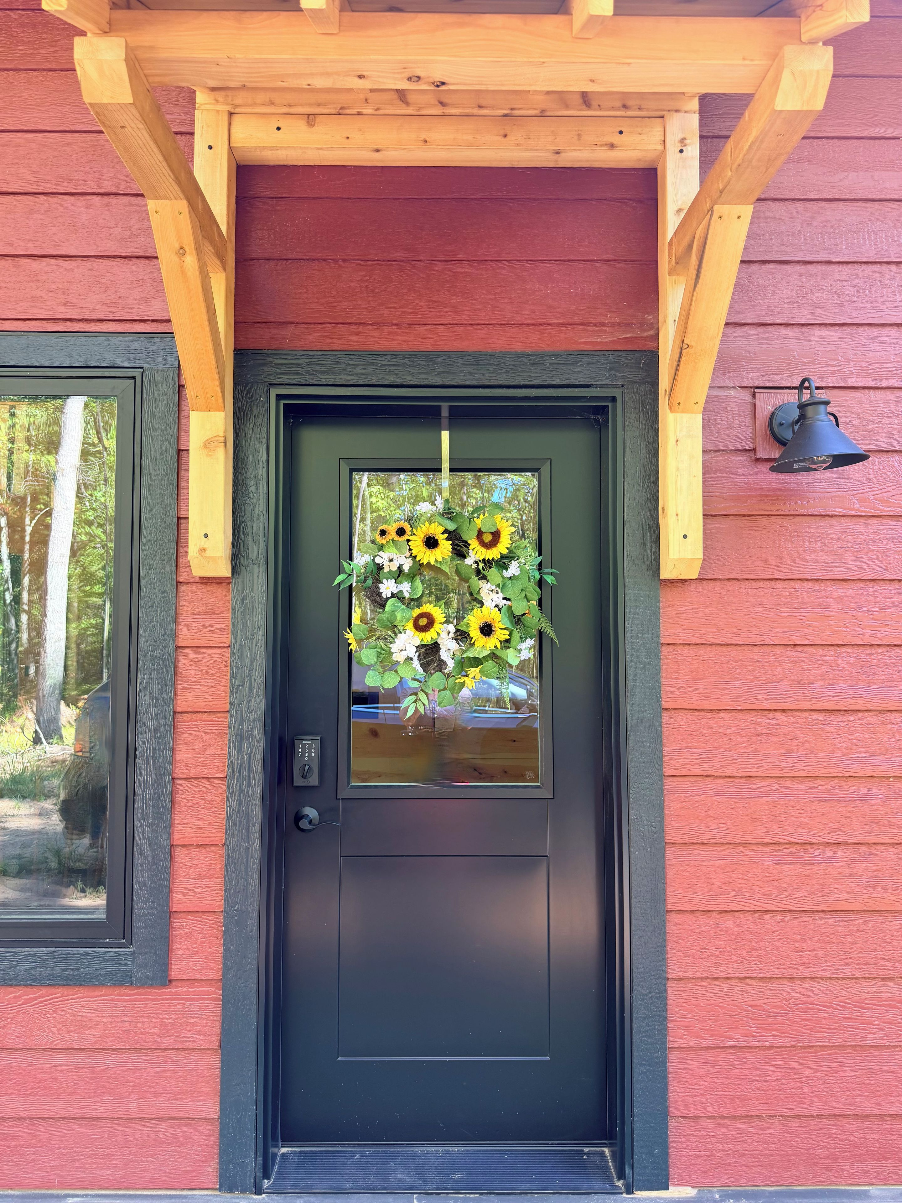 A wooden door with a black frame, a glass panel, and a floral wreath.