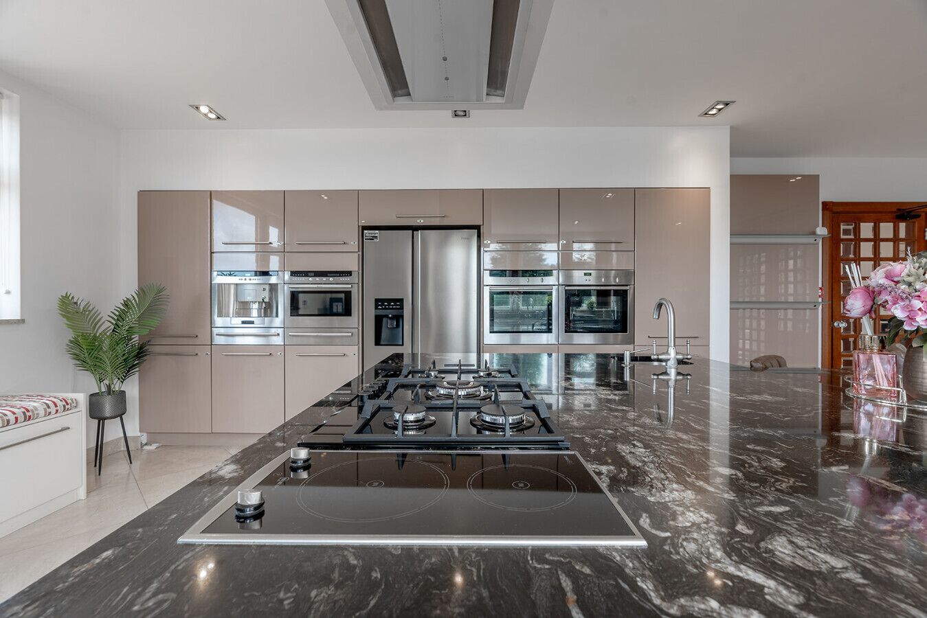 Een moderne keuken met een centraal eiland, roestvrijstalen apparatuur en een marmeren aanrecht.
