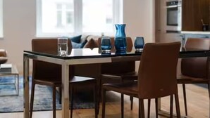 A dining area with a glass table, chairs, and a blue vase. - Prime Central 2BR Apartment Covent Garden (London)