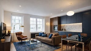 A modern living room with a sofa, coffee table, and dining area. - Prime Central 2BR Apartment Covent Garden (London)