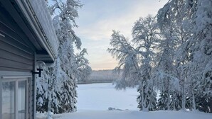 Paisagem coberta de neve com uma casa e árvores.