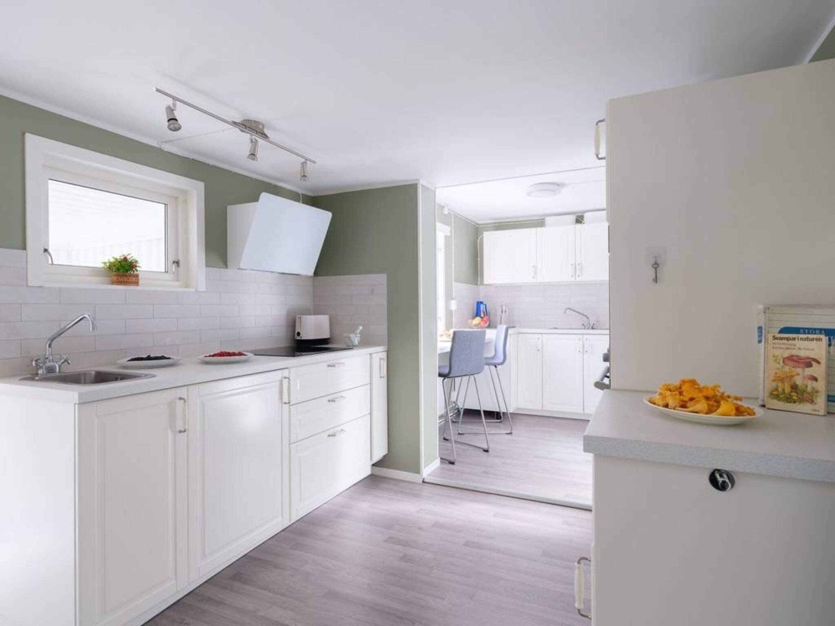 A modern kitchen with white cabinets, a built-in oven, and a window above the sink.