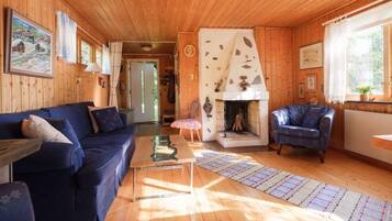 Ein Holzblockhaus-Interieur mit Sofa, Sesseln, Kamin und einem Bild an der Wand.