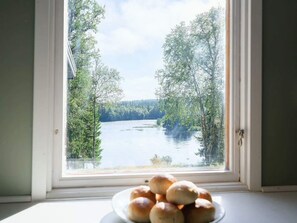 A window view of a lake with trees, and a plate of rolls on the windowsill. - 6 Person Holiday Home in Duved (Duved)