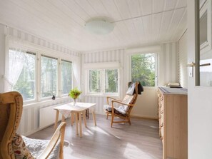 A room with a dining table, chairs, a window with curtains, a wooden chair with a blanket, and a radiator. - 6 Person Holiday Home in Duved (Duved)