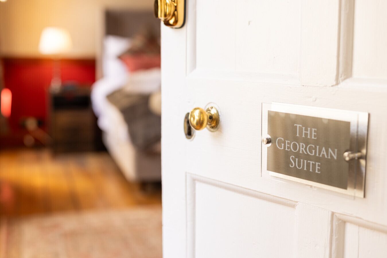Eine weiße Tür mit Messingklinke und einem Schild mit der Aufschrift 'The Georgian Suite'.