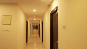 Un couloir d’hôtel avec des portes des deux côtés, un interrupteur sur le mur et un luminaire au plafond.