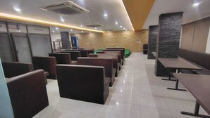 Un intérieur de restaurant propre et moderne, avec des banquettes et des tables, des toilettes bien visibles et un mur d’accent en pierre.