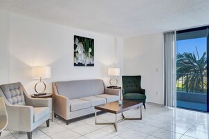 Uma sala de estar moderna com um sofá, duas poltronas, uma mesa de centro e um quadro na parede.