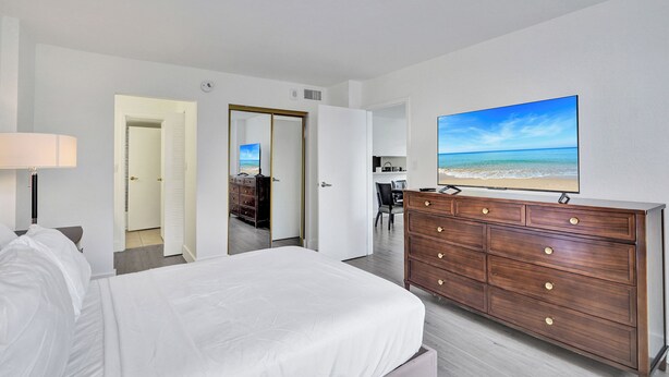 Ett hotellrum med en säng, en byrå, en tv och utsikt över stranden.