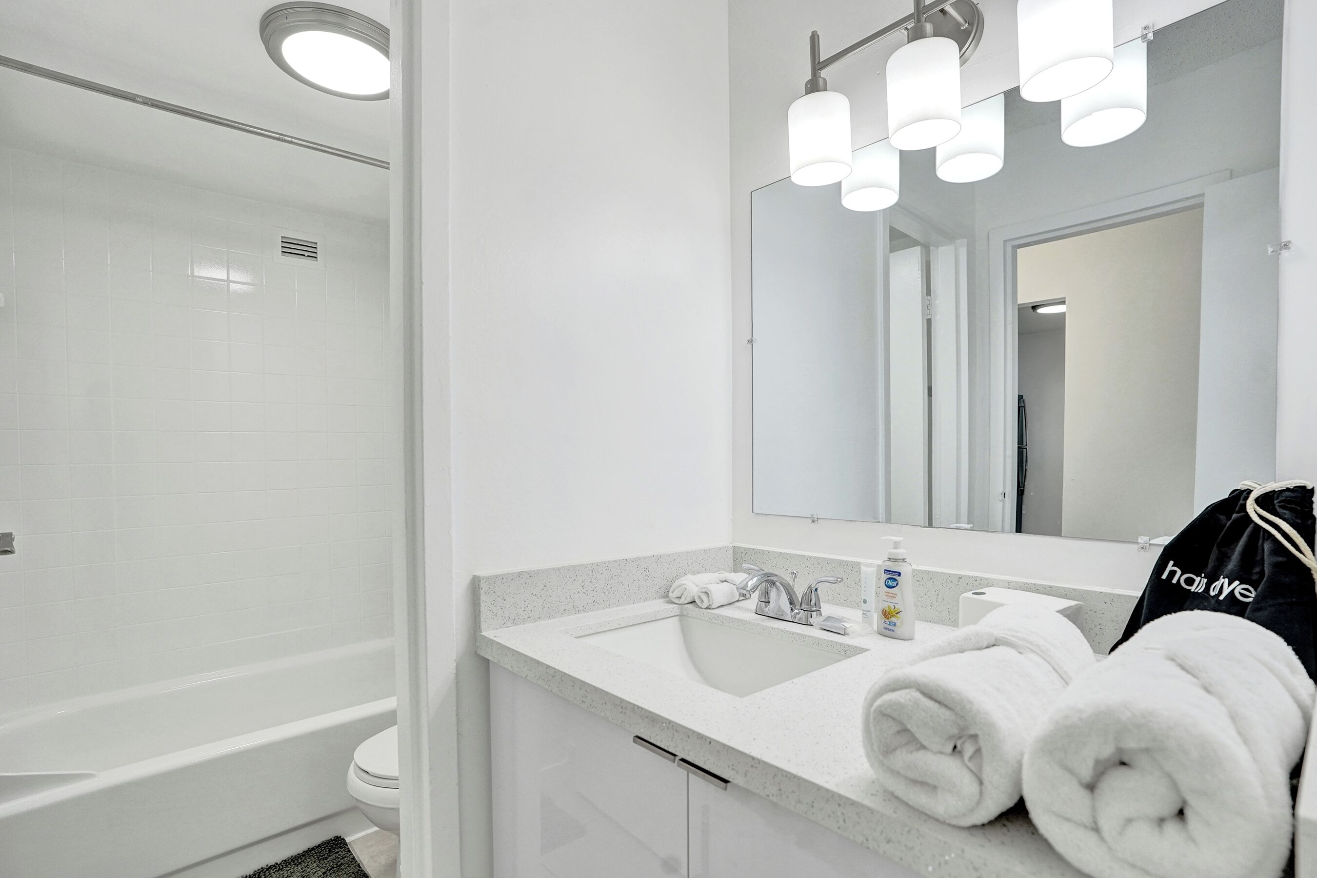 A modern bathroom with a white sink, mirror, and shower.