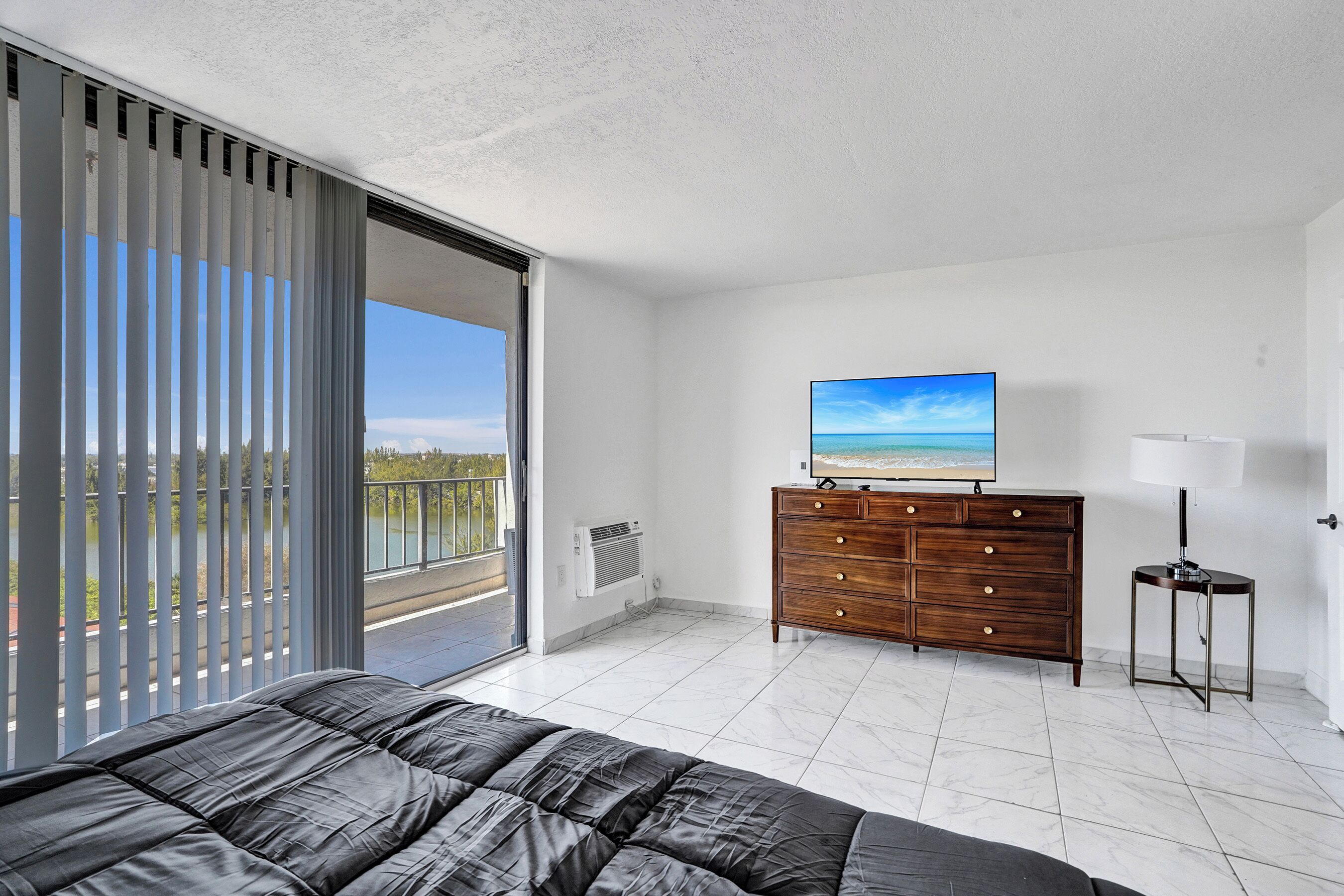 Una camera da letto con un letto, una cassettiera, una TV e un balcone con vista.
