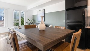 A modern kitchen with a black refrigerator, a dining table with chairs, and a vase on the table. - Light-Filled Artsy Stay in Little Tokyo (Los Angeles)
