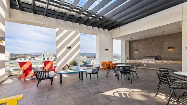 A rooftop patio with outdoor seating, a grill, and a view of the cityscape. - Light-Filled Artsy Stay in Little Tokyo (Los Angeles)