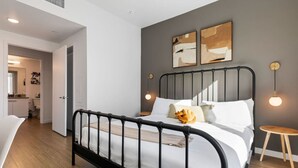 A modern bedroom with a black metal bed frame, white bedding, and two abstract paintings on the wall. - Light-Filled Artsy Stay in Little Tokyo (Los Angeles)