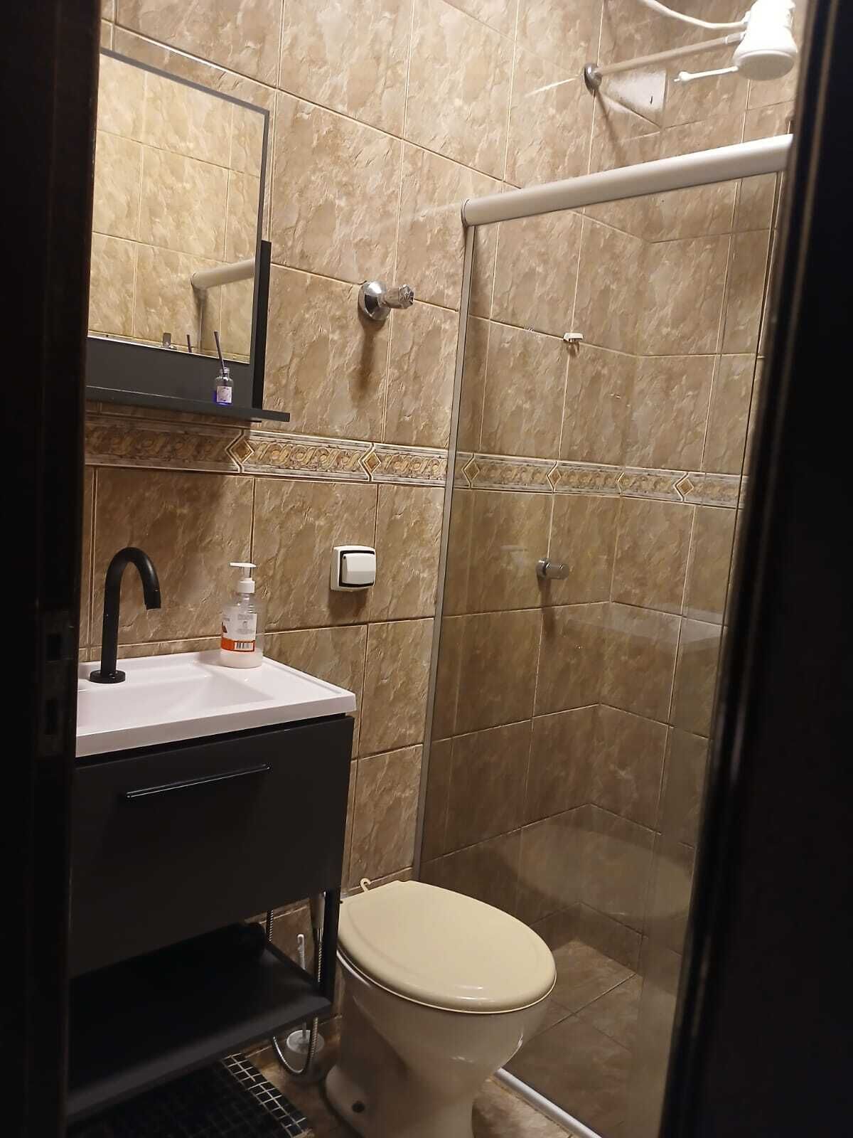 Een badkamer met een wastafel, spiegel, toilet en douche.