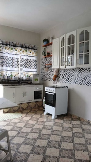 A kitchen with white cabinets, a stove, and a tiled backsplash.
