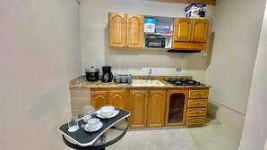 Une cuisine compacte avec des meubles en bois, un plan de travail, un évier, une cuisinière et une petite table à manger avec de la vaisselle.
