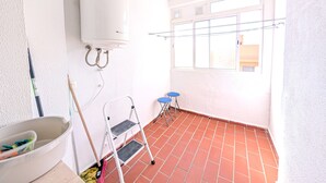 Ein Zimmer mit einem weißen Heizgerät, einer Stehleiter, einem Eimer und einem Besen.
