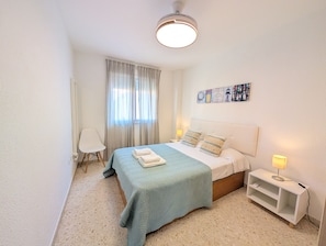 A bedroom with a bed, a nightstand, a chair, and a window with curtains. - 139 Livingtarifa Gonga House (Tarifa)