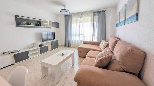 Ein modernes Wohnzimmer mit einer Couch, einem Fernseher, einem weißen Couchtisch und einem Deckenventilator.