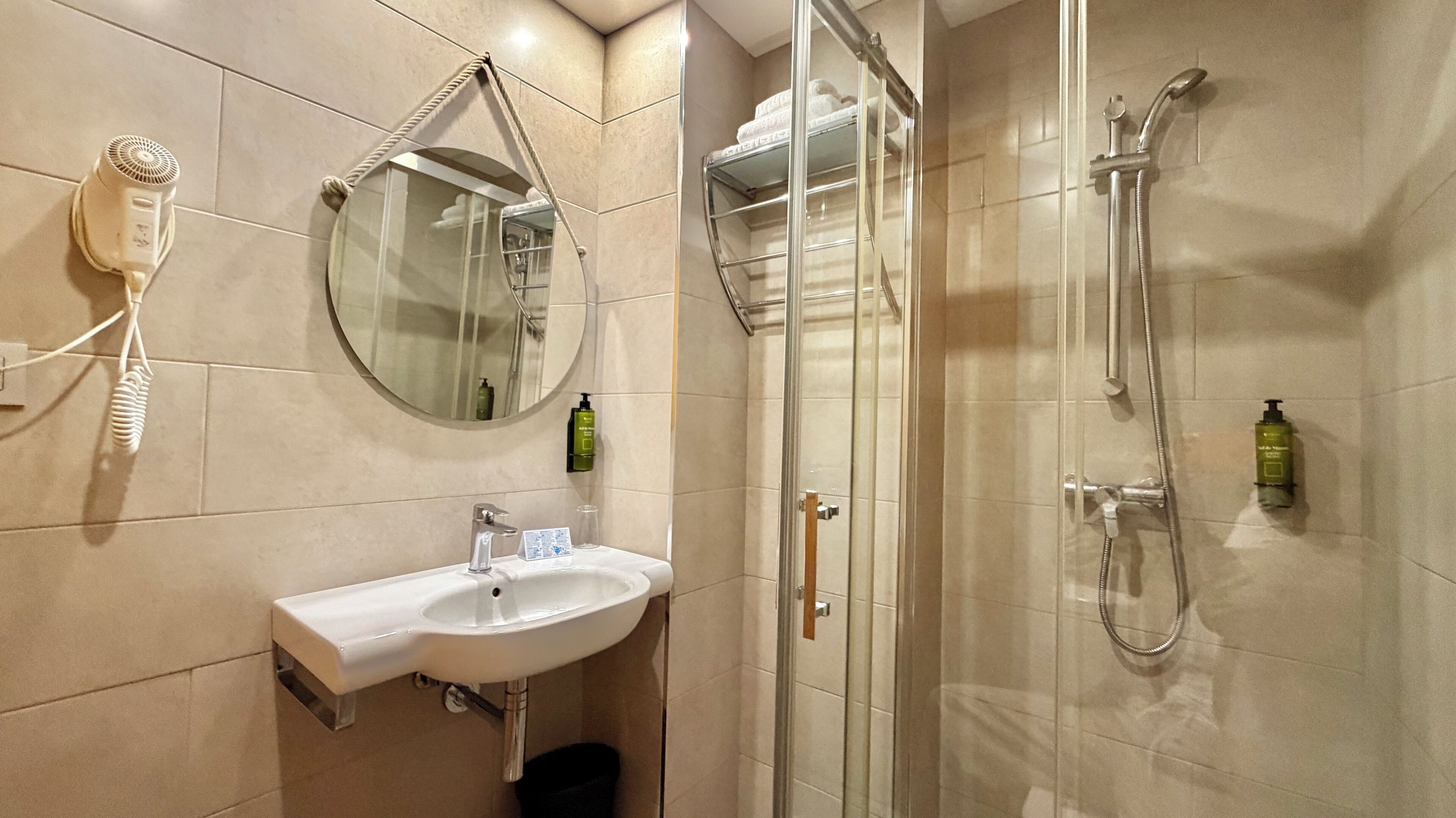 Une salle de bain équipée d’un lavabo, d’un miroir, d’un sèche-cheveux et d’une douche.