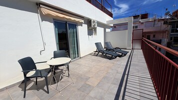 A balcony with a table and chairs, a sliding door, and a red railing.