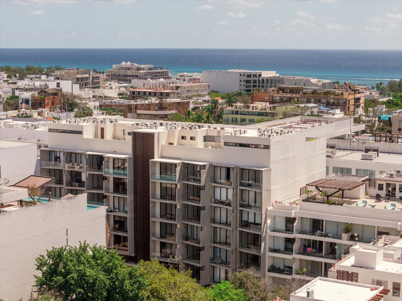 Un hôtel à plusieurs étages doté de balcons, d’une piscine sur le toit et offrant une vue sur l’océan.