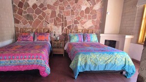 A room with two beds, a stone wall, a fireplace, and a nightstand. - SS 5A Cabaña rustica frente al malecón de La Paz (La Paz)