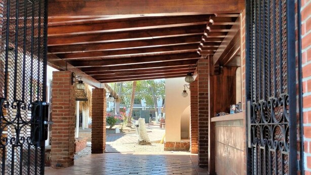 An open covered walkway with tiled flooring, brick walls, and metal gates. - SS 5A Cabaña rustica frente al malecón de La Paz (La Paz)