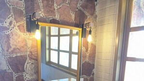 A room with a stone wall, a wooden vanity with a mirror, and a window. - SS 7A Cabaña rustica frente al malecón de La Paz (La Paz)