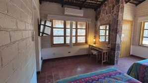 A room with a desk, a bed, a window with a view, and a stone wall. - SS 5B Cabaña rustica frente al malecón de La Paz (La Paz)