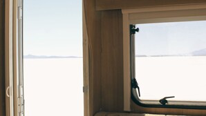Une fenêtre donnant sur un paysage plat, un intérieur en bois et une poignée en métal.