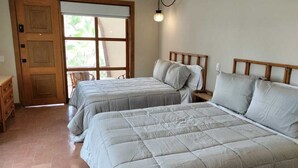 Ein Schlafzimmer mit zwei Betten, einer Holztür, einem Fenster und einer Pendelleuchte.