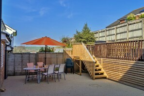 Une terrasse avec une table et des chaises, une clôture en bois et une vue sur la campagne.